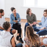 um grupo de 8 pessoas sentadas em cadeiras, em forma de círculo, conversando