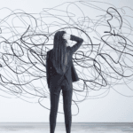 uma mulher, olhando para uma parede rabiscada. aparentemente confusa com o desenho