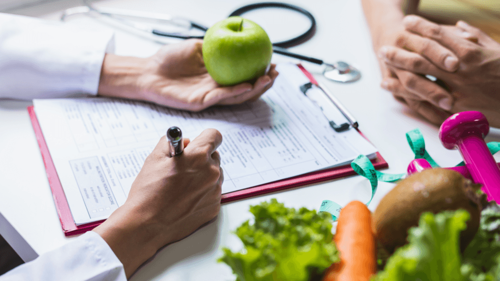 nutricionista segurando uma maçã e escrevendo. uma cesta de salada compõe a cena