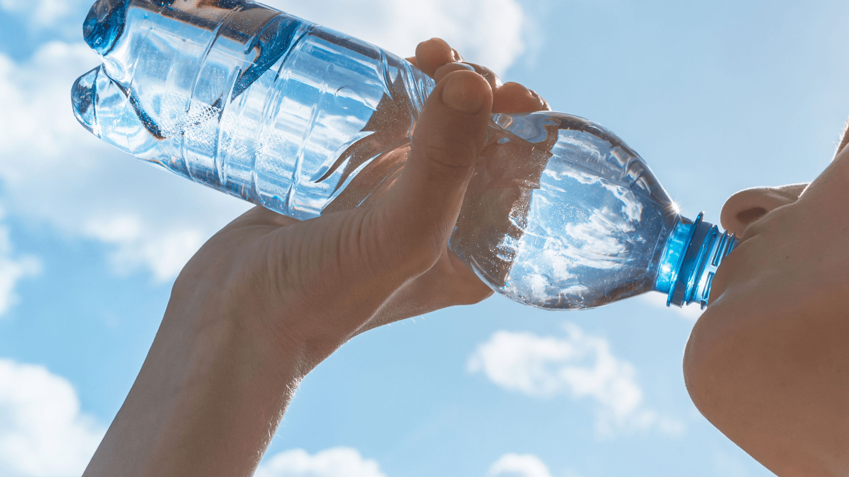 uma mulher bebendo uma garrafa de água com o céu ensolarado ao fundo